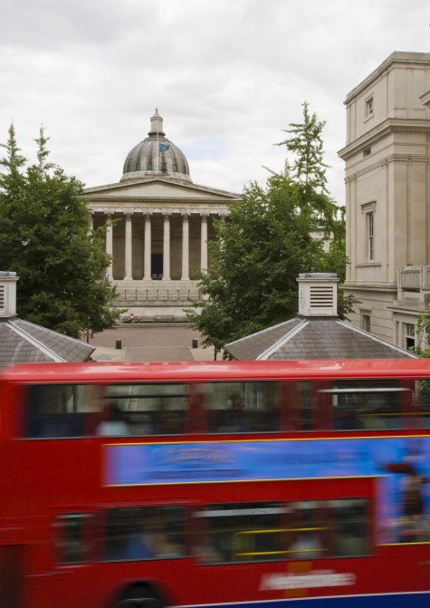 UCL Portico viewed from the road. A red bus is driving past.